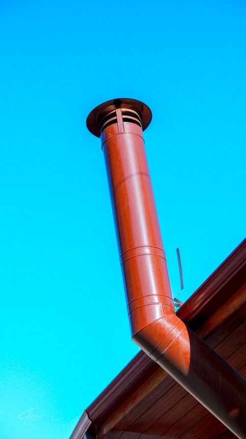 Free Close-up of a red chimney on a roof against a clear blue sky. Stock Photo