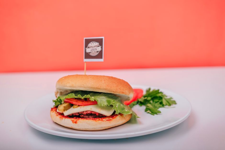 Hamburguesa vegana en plato, con símbolo de advertencia de contaminación química