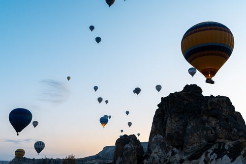 Free Hot air balloons floating over a rocky landscape at dusk, capturing the serene beauty of a twilight adventure. Stock Photo