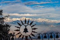 Scenic view of the Himalayan mountains framed by decorative bells in the foreground.