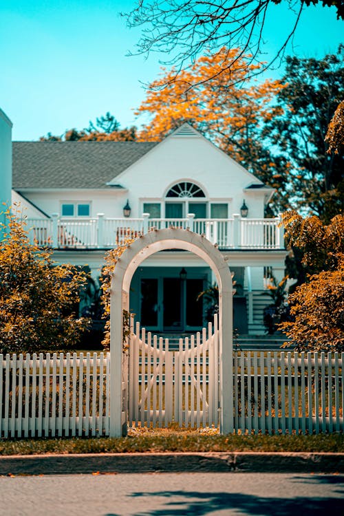 White and Gray 2-storey House Behind White Gate Panel