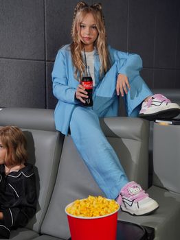 Teen girl enjoying movie theater with popcorn and soda. Casual fun setting.