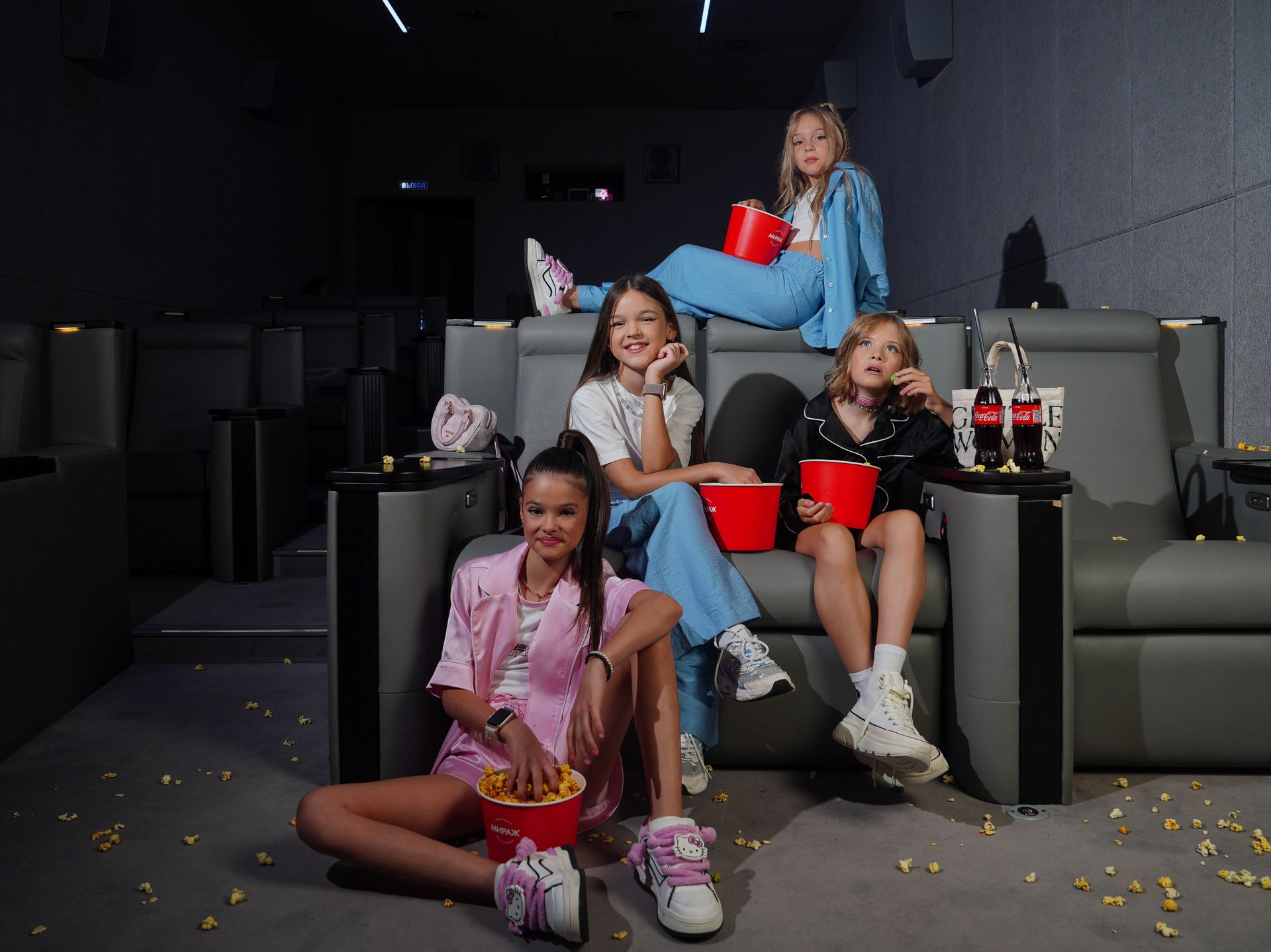 Group of children in a cozy home theater enjoying a movie with snacks.