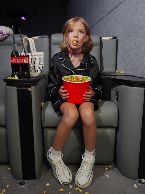 Free Young girl in a theater with popcorn and soda, embracing movie night fun. Stock Photo