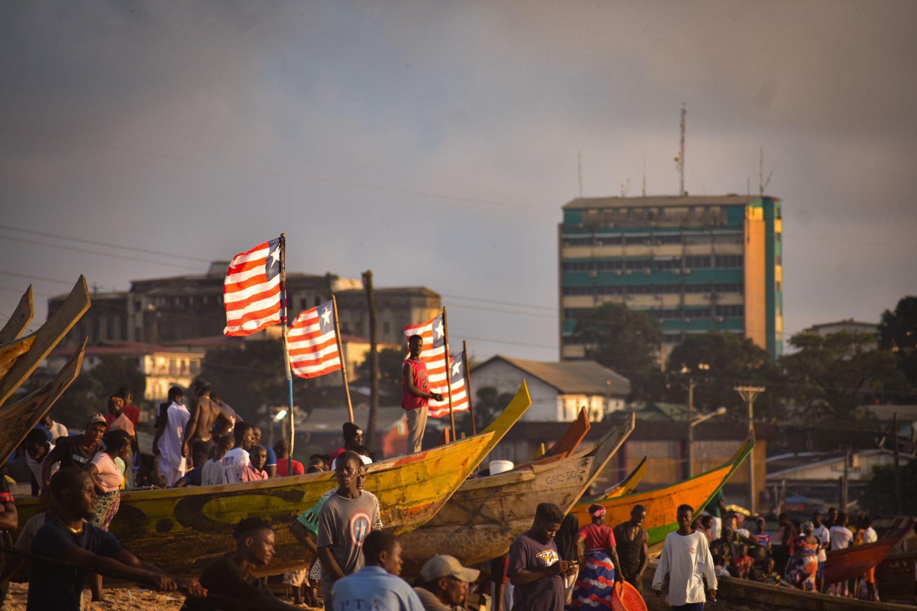 Vibrant scene of fishermen and canoes along the Monrovia coast during day.