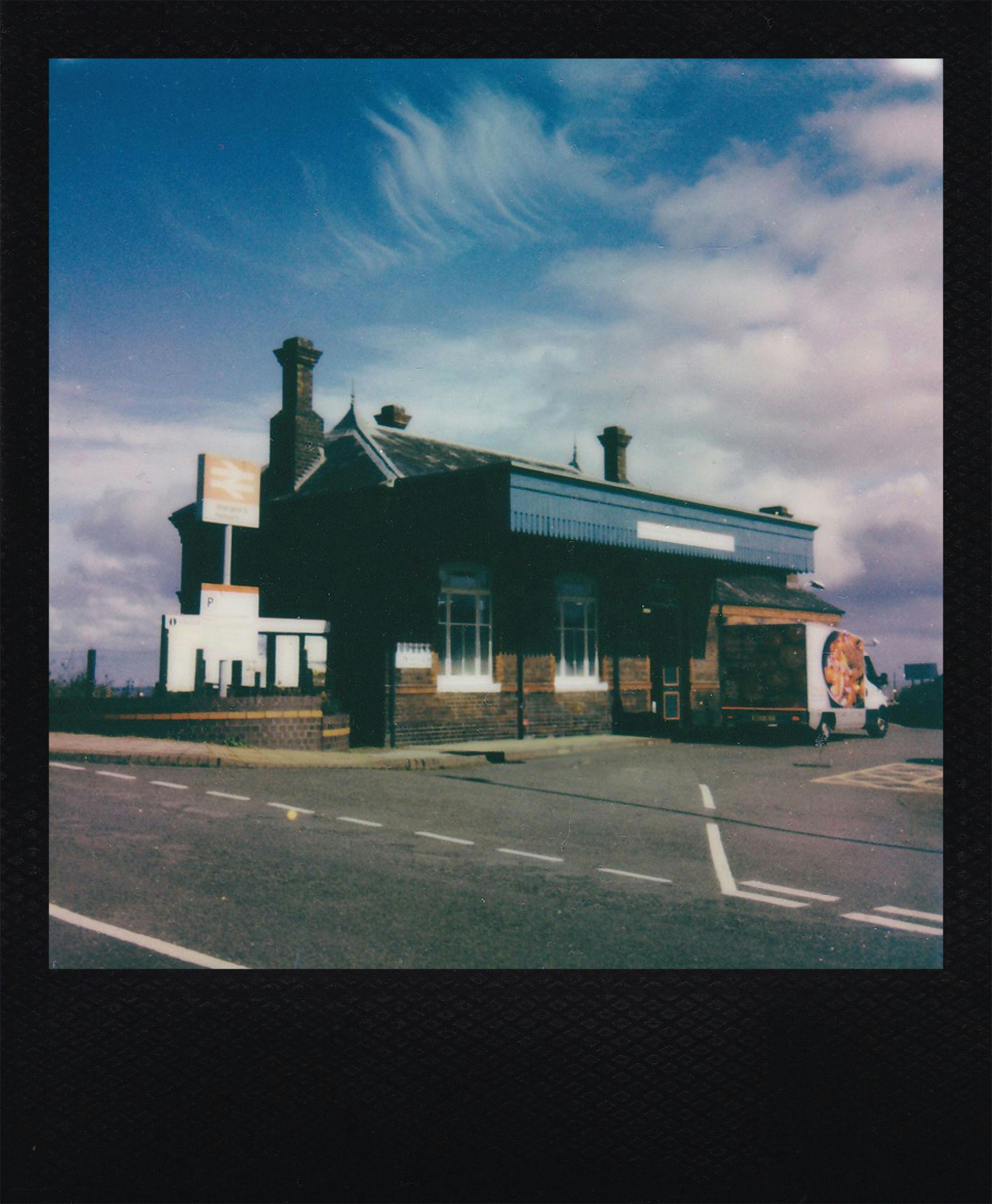 Capture of a vintage train station building on a bright day with cloud-filled sky.