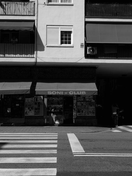 Free A monochrome view of a city storefront with a zebra crossing in the foreground. Stock Photo