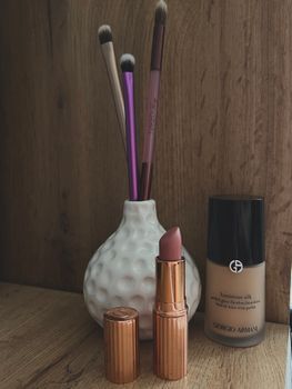 Stylish arrangement of makeup essentials with brushes, lipstick, and foundation for beauty enthusiasts.