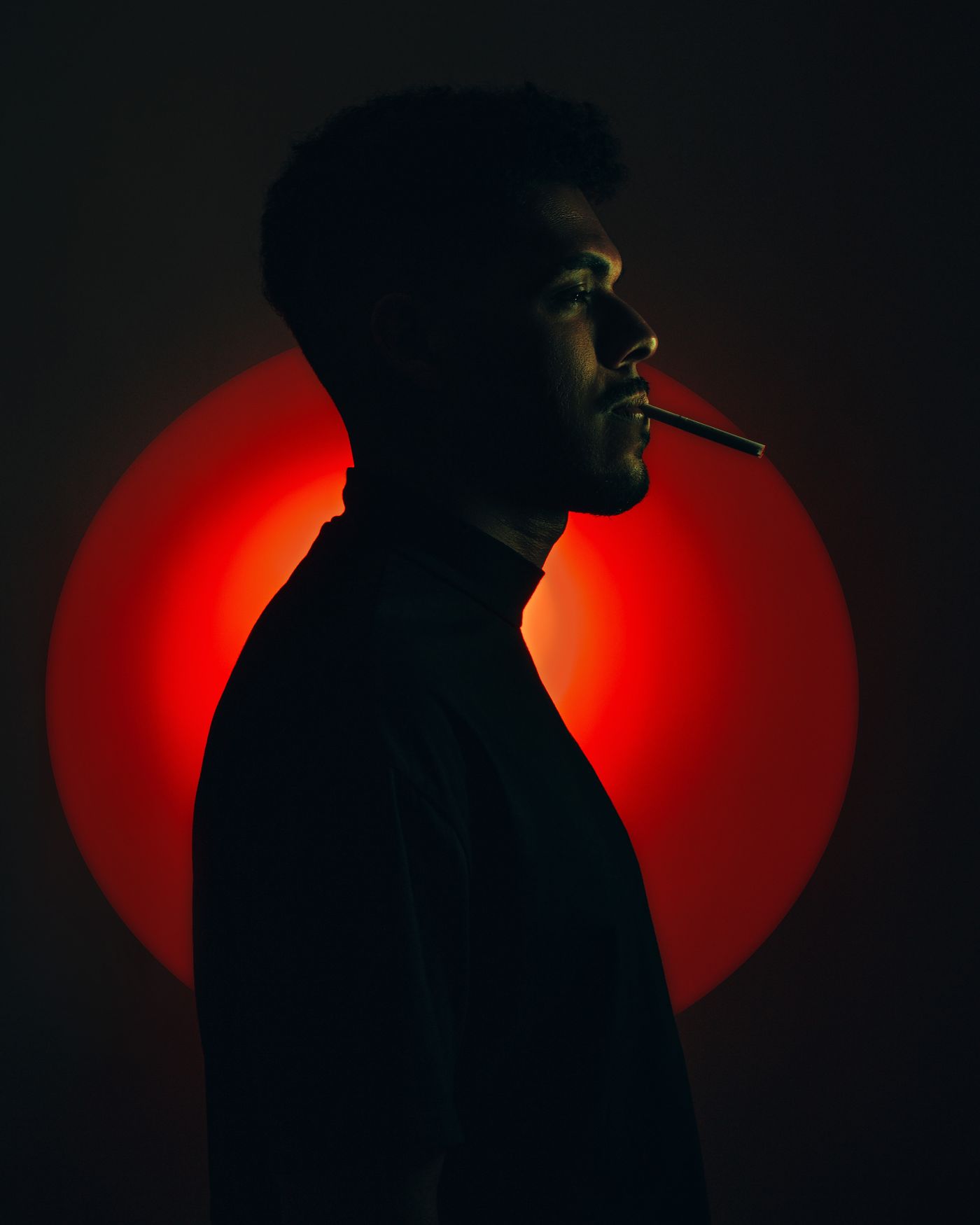 Silhouette of a man smoking against a wash of red light
