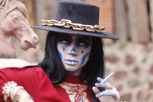 Free A vibrant portrait featuring Day of the Dead makeup with dramatic costume elements outdoors. Stock Photo