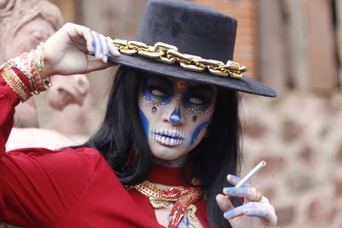 Free Colorful Day of the Dead inspired portrait with vibrant makeup and accessories outdoors. Stock Photo
