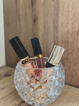 A collection of stylish lipsticks in a crystal holder set on a wooden table, showcasing beauty essentials.