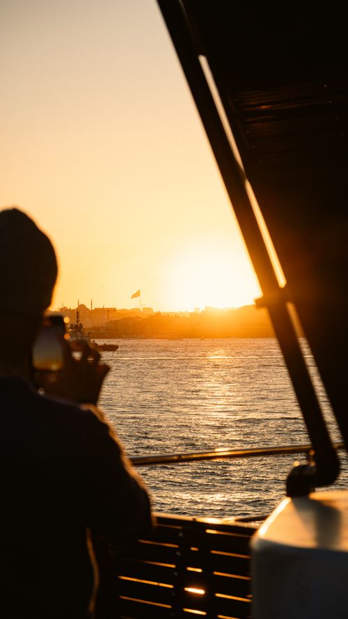 Free A person captures a stunning sunset over calm waters, creating a serene moment. Stock Photo