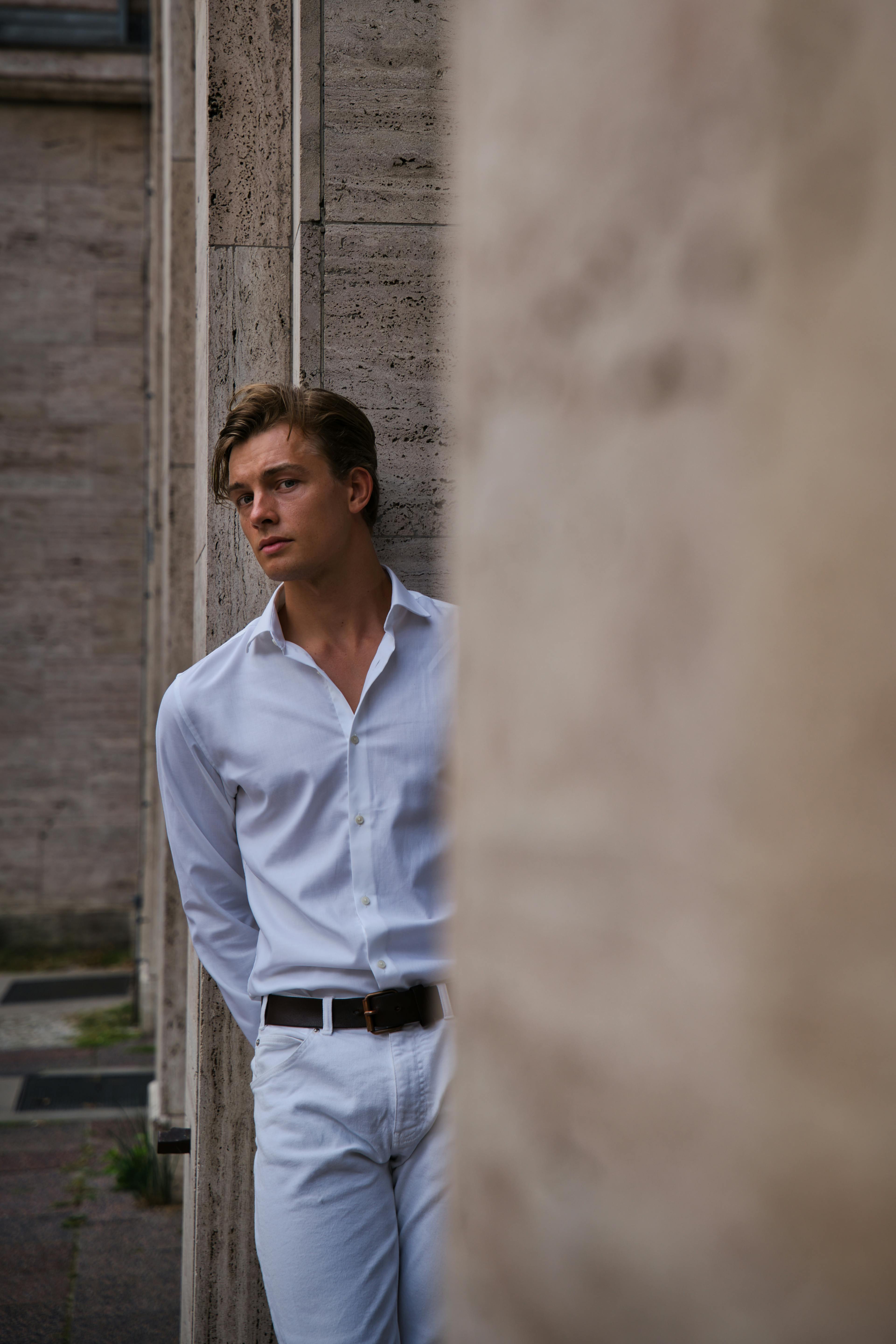 Young male model posing in a stylish white outfit during an outdoor photoshoot in Berlin.