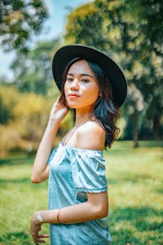 一位戴着黑色帽子的时尚女性在阳光明媚的户外摆着姿势