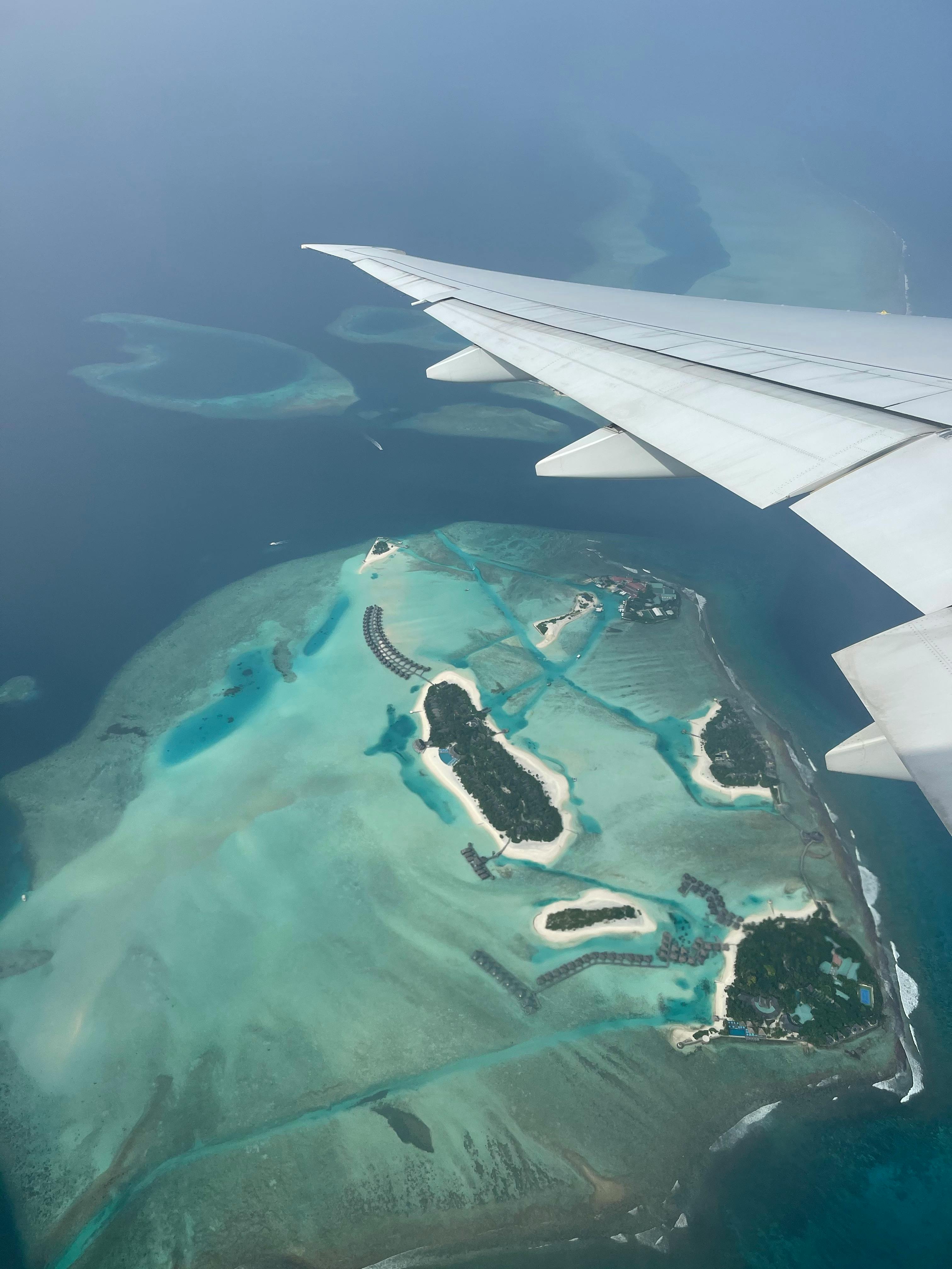 Stunning aerial view of the Maldives' blue waters and islands as seen from an airplane window.