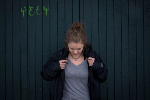 Mujer Sosteniendo Chaqueta Junto A La Pared