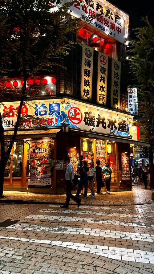Free Lively night scene at a bustling street in Tokyo with illuminated signs and pedestrians. Stock Photo