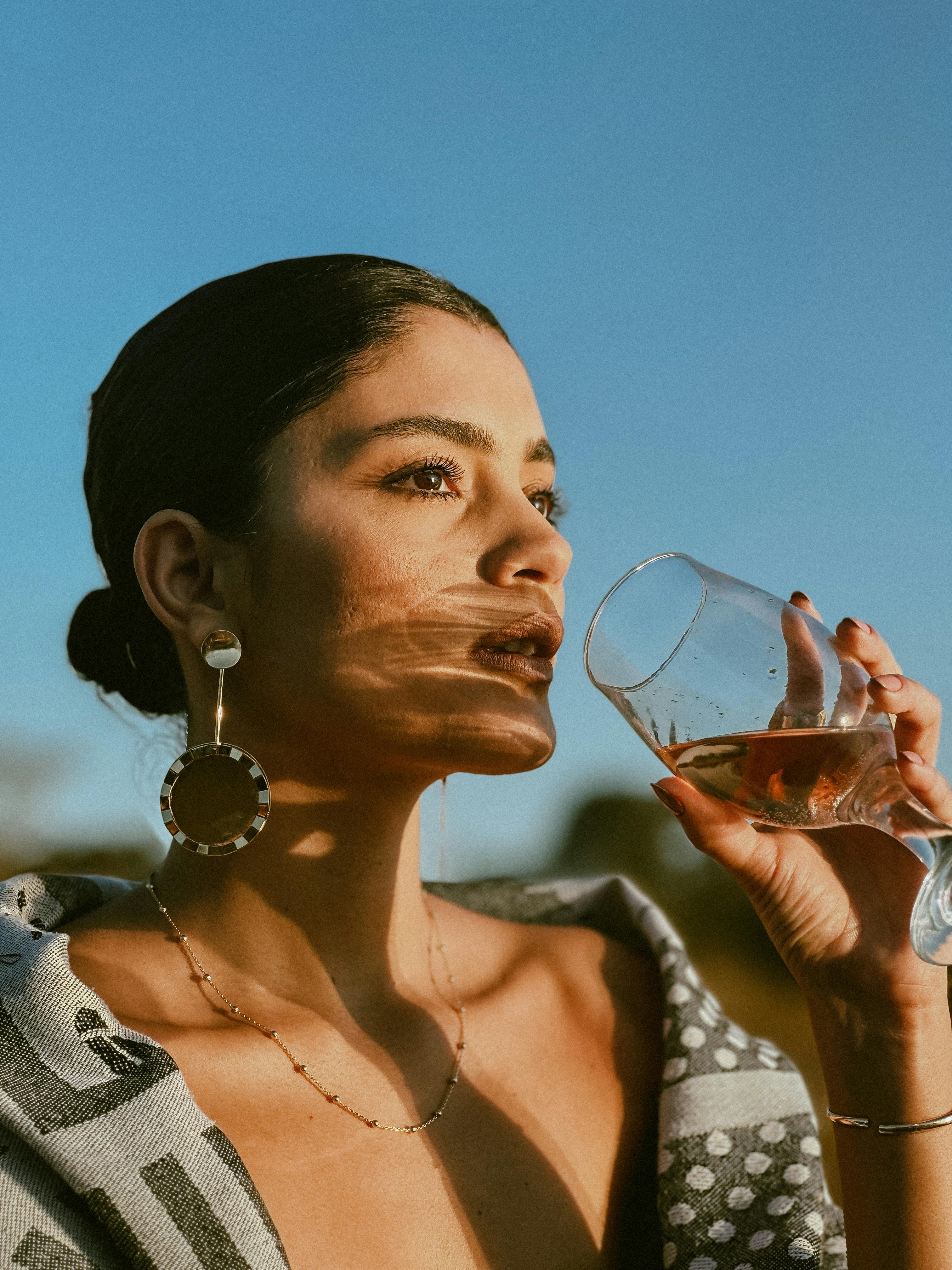 elegant woman enjoying a drink outdoors at sunset