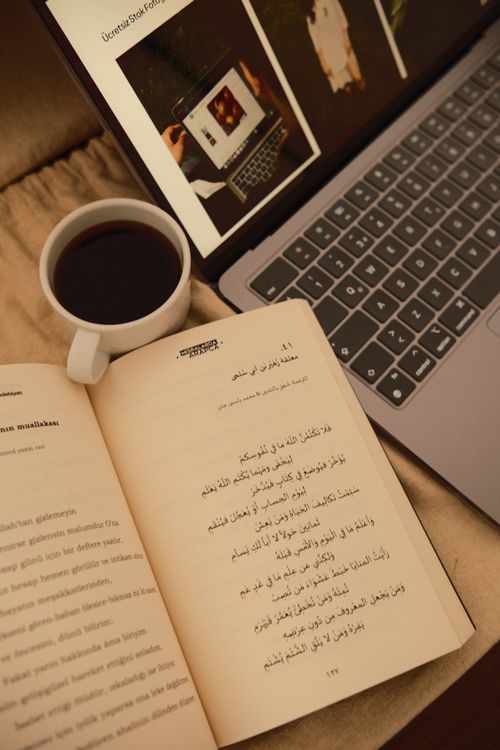 Free Open book and laptop with coffee, perfect for a cozy reading setting. Stock Photo