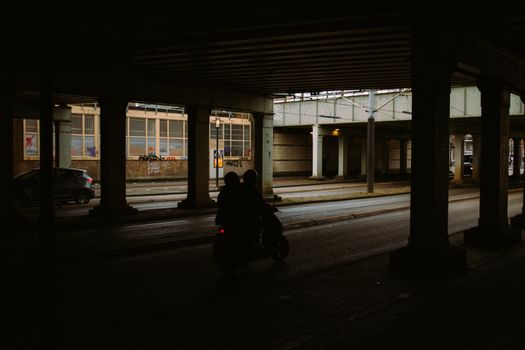 Silhouette of a scooter under a bridge in Amsterdam, capturing urban life and movement.