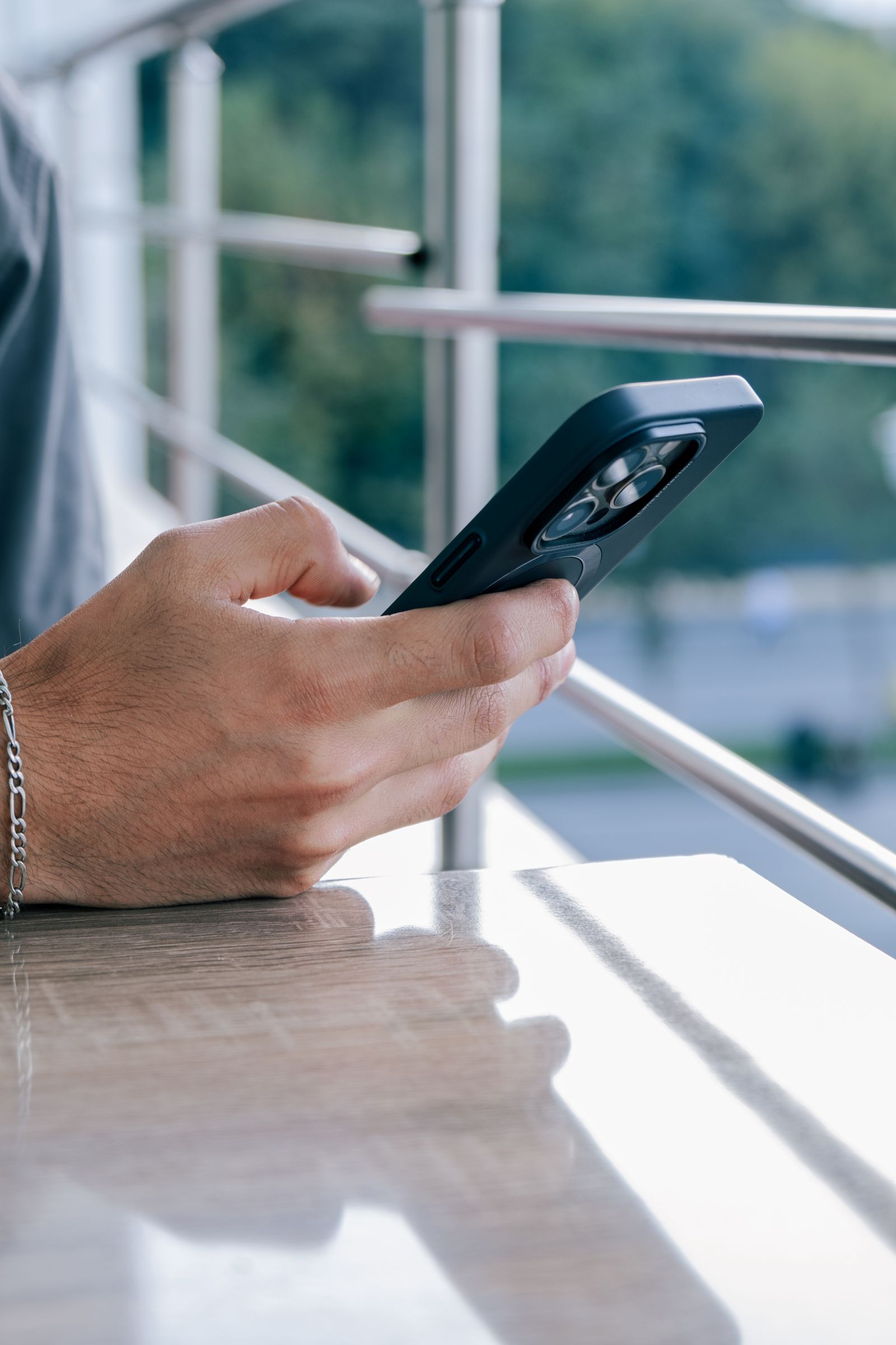A person checking a bird-identification app on a smartphone outdoors near a backyard feeder