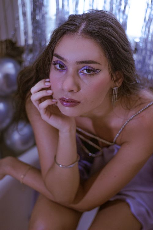 Free A woman in glamorous attire with shimmering makeup posing indoors with a chic atmosphere. Stock Photo