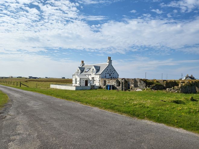 White cottage on a coastal road under a clear sky — photo by Scott Fenwick on Pexels