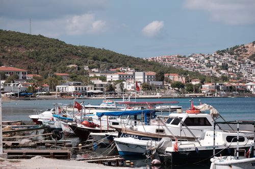 Free Charming Foça marina scene showcasing docked boats against a backdrop of hillside homes in Izmir, Türkiye. Stock Photo