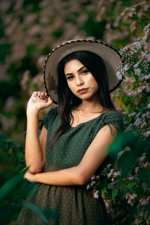 Free Elegant portrait of a woman in a green dress and hat surrounded by nature. Stock Photo