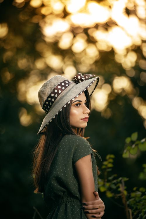 Free Woman wearing a polka dot hat in a serene outdoor setting at sunset. Stock Photo