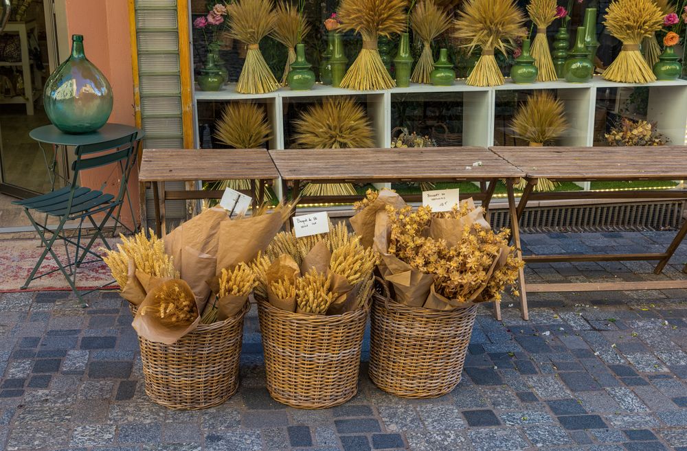 Buchete de flori uscate și spice în coșuri de răchită, la o tarabă provensală