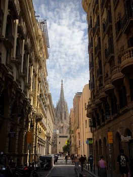 Charming view of Barcelona's Gothic Cathedral from a bustling street lined with historic buildings.