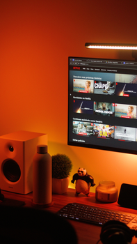 Warmly lit home office setup with a computer monitor displaying a streaming service interface.