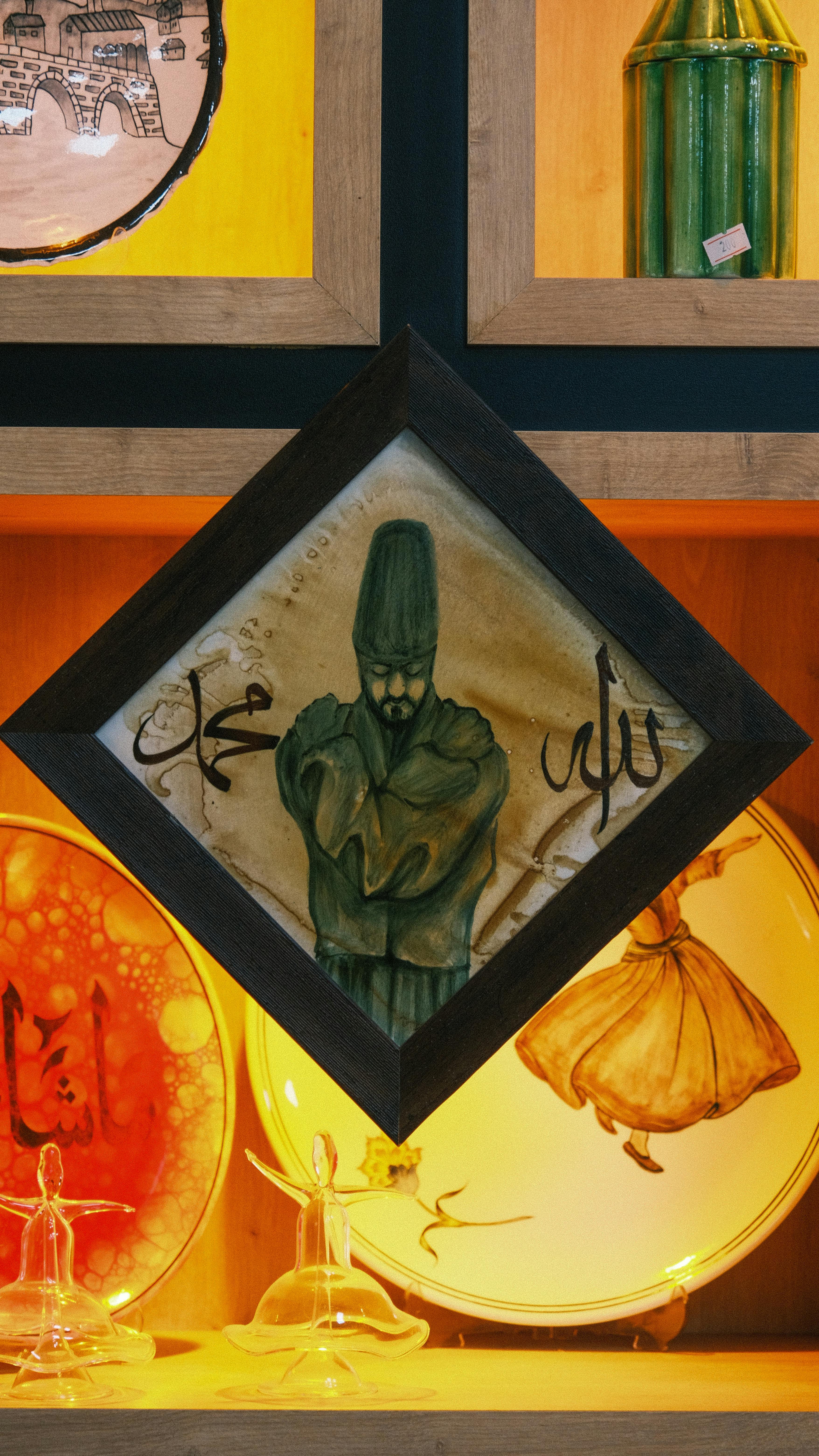 Framed Sufi artwork and decorative plates in a warm-lit display.