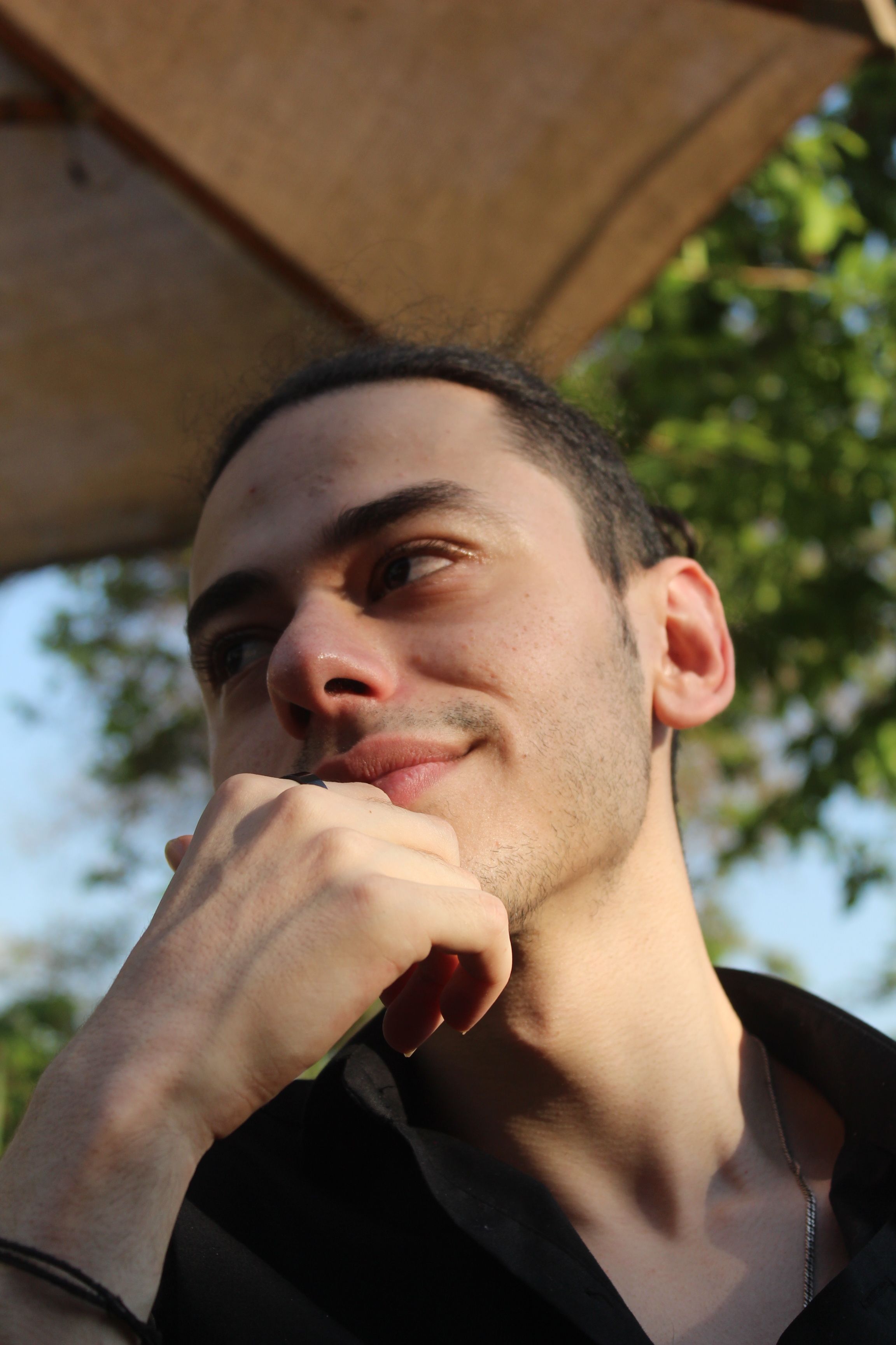 Close-up outdoor portrait of a thoughtful young man in natural light.