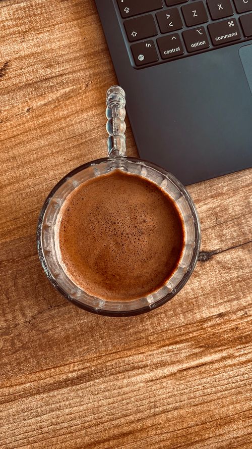 Free Glass mug of coffee with laptop on textured wooden desk. Perfect for work and productivity themes. Stock Photo