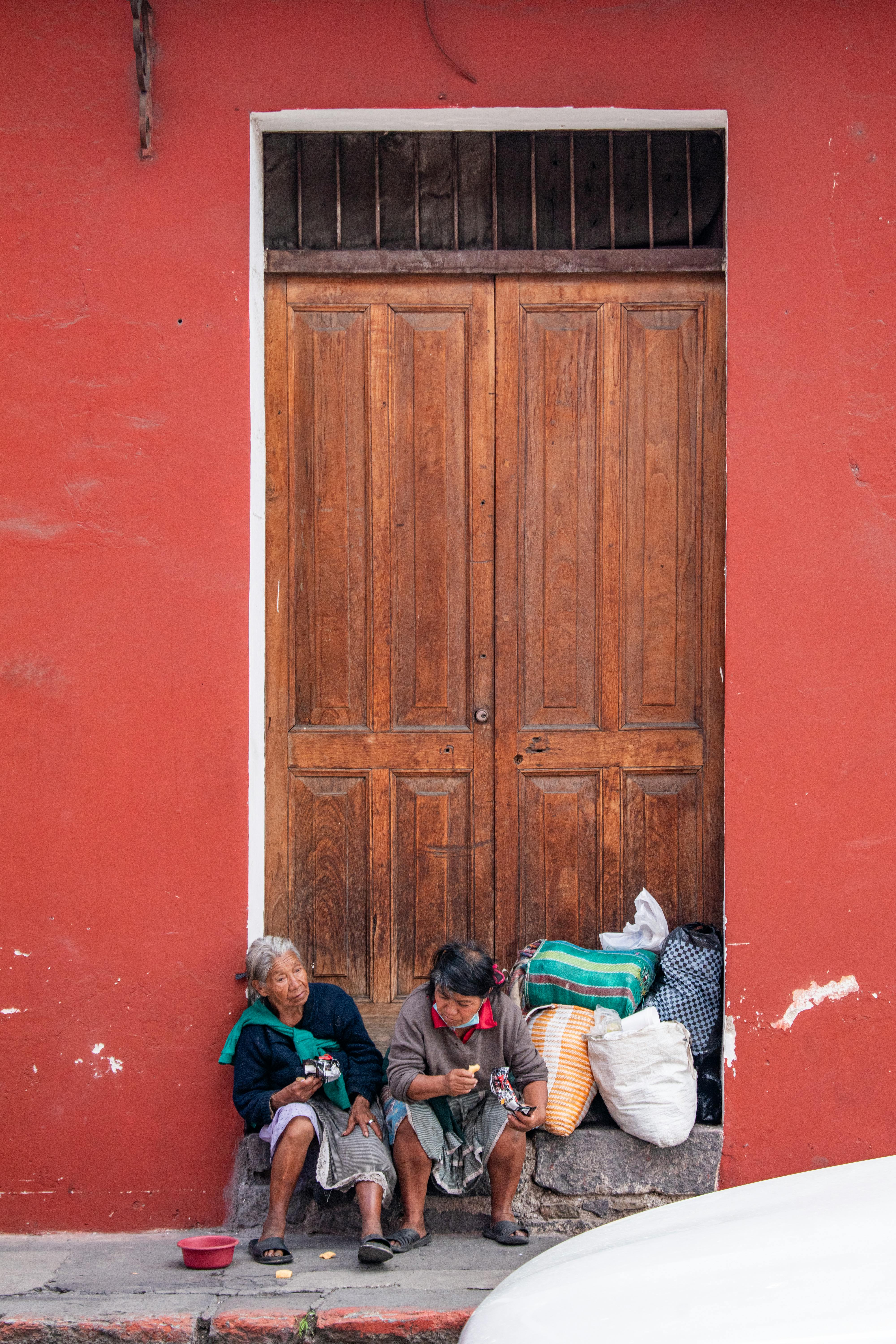 Dos Personas Mayores Descansando Junto A Una Pared Colorida En Antigua