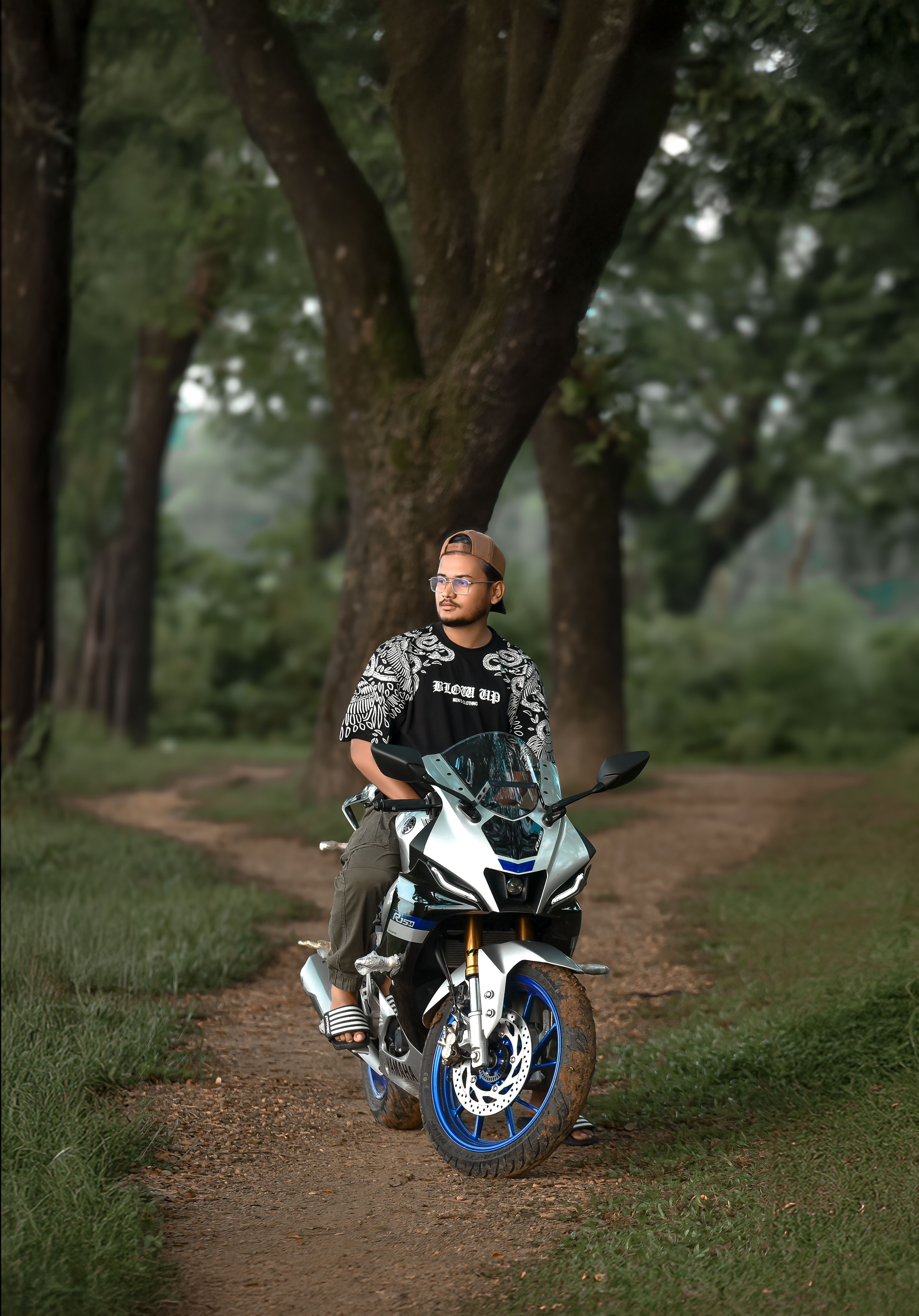 Man riding a motorcycle through a lush green forest path.