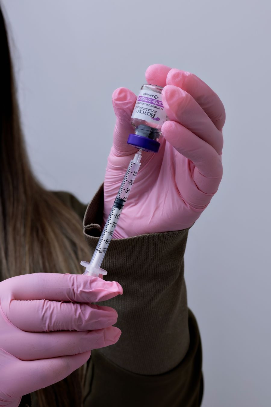 Close-up of a healthcare professional preparing a syringe and vial for an aesthetic medical treatment