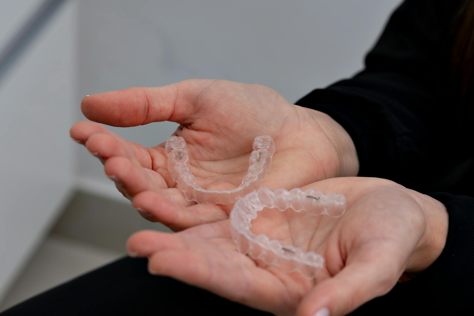 Hands holding clear dental aligners in a modern dental office in Belo Horizonte.