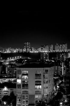 Black and white cityscape of Istanbul's skyline at night, showcasing high-rise buildings and city lights.