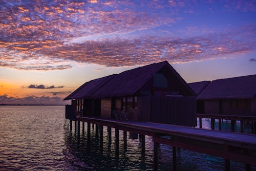 Breathtaking sunset view of overwater bungalows in a tropical paradise with vibrant skies.