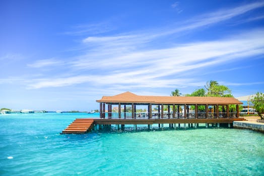 Scenic overwater pavilion on a beautiful tropical island with turquoise waters and vibrant sky.
