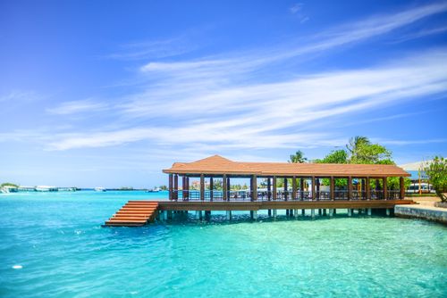 Free Scenic overwater pavilion on a beautiful tropical island with turquoise waters and vibrant sky. Stock Photo