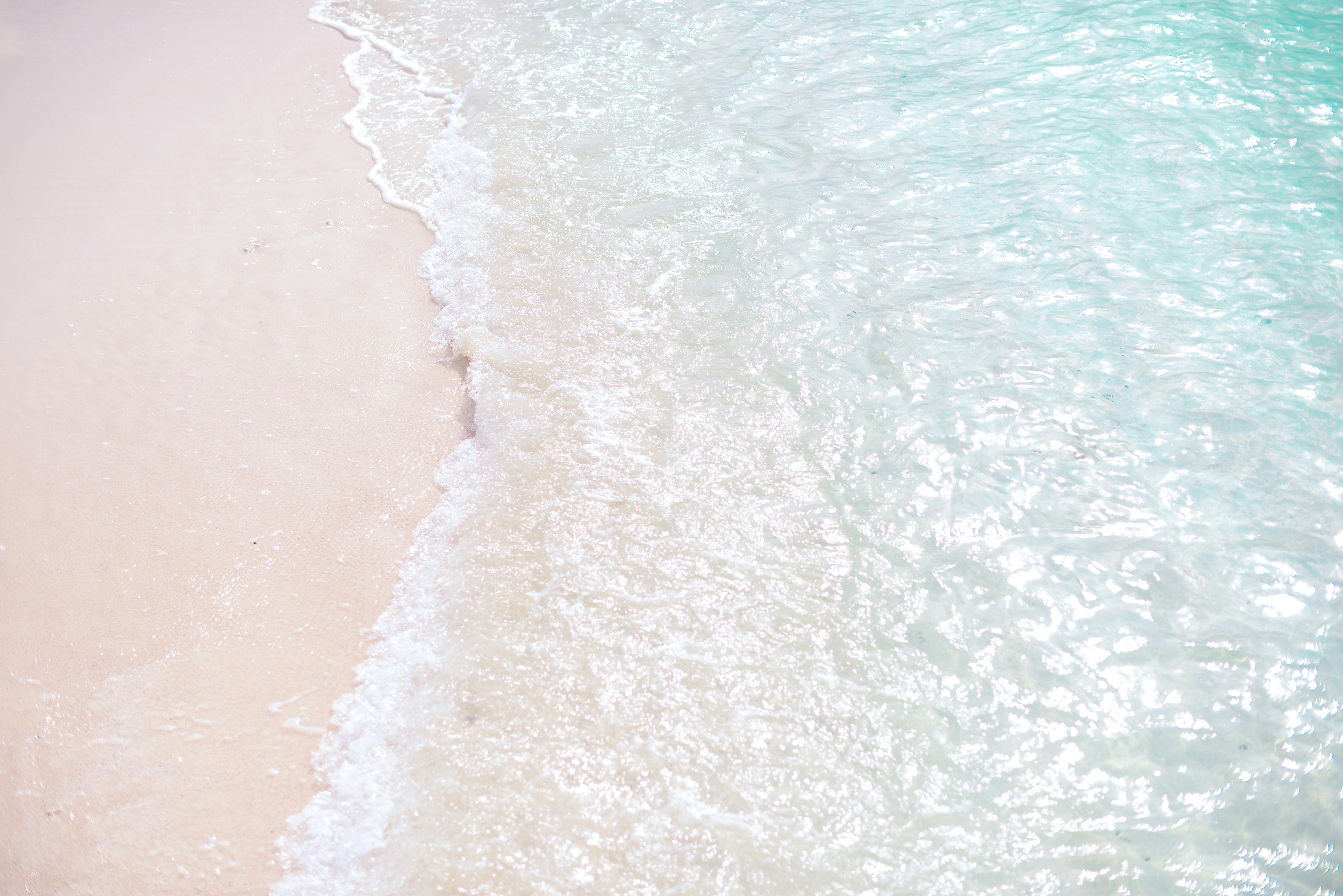 Tranquil scene of waves on a white sand beach, clear turquoise waters.