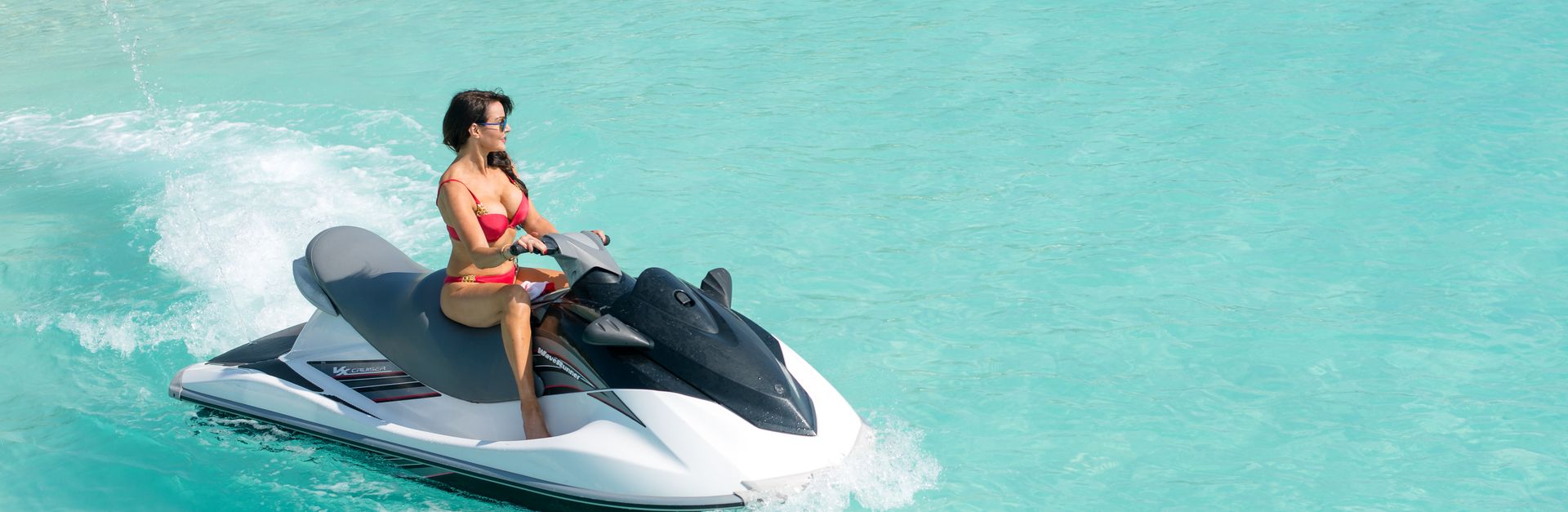 Vibrant image of a woman enjoying a jet ski ride in clear turquoise water.