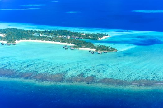 Stunning aerial view of a tropical island with turquoise waters and white sand beaches in the Maldives.