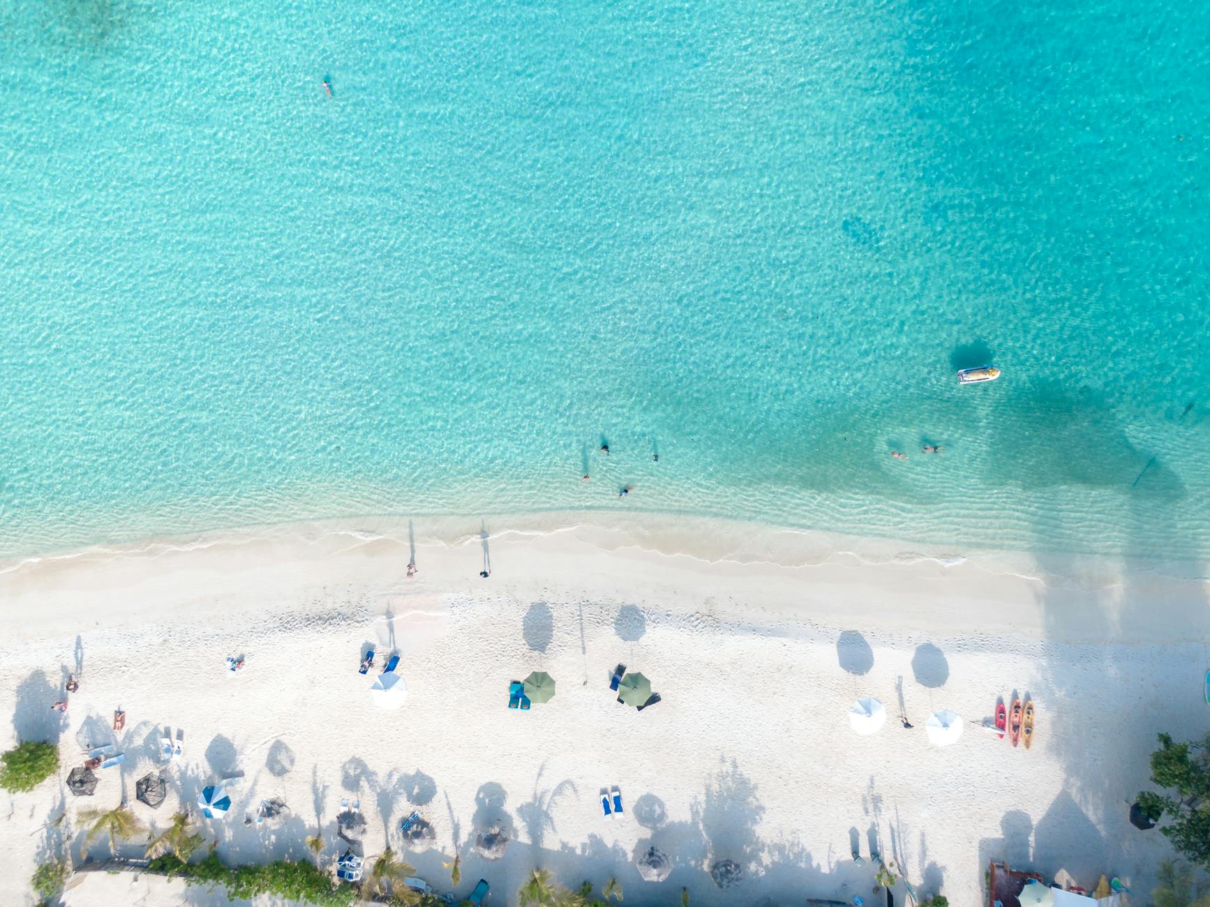 A stunning aerial view of a tropical beach with white sand and clear turquoise water, perfect for relaxation.