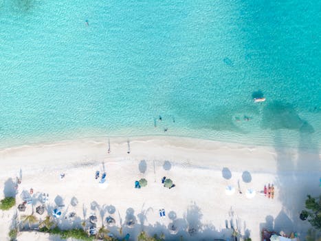 A stunning aerial view of a tropical beach with white sand and clear turquoise water, perfect for relaxation.